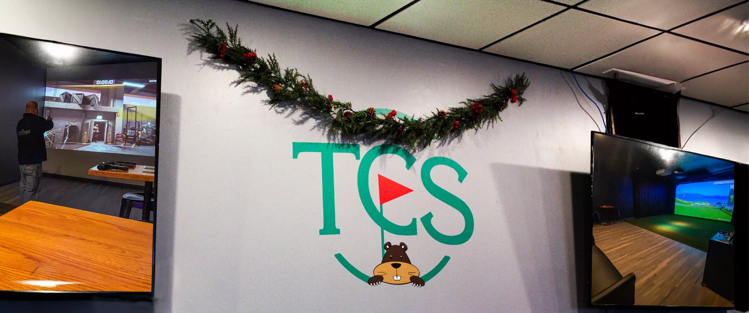 TCS logo with festive garland and TVs beside it showing simulator bays.